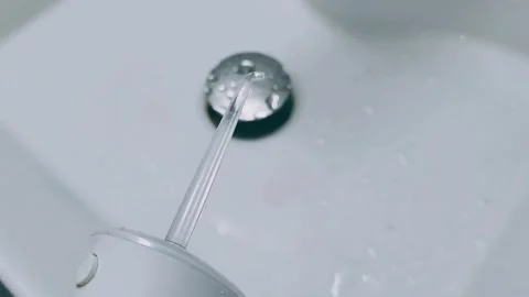 Close-Up of a Water Flosser Tip Over a Wet Sink Stock Footage 291701407