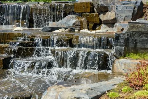 Close-up of water flowing down large stones in the cascading waterfall. Stock Photos