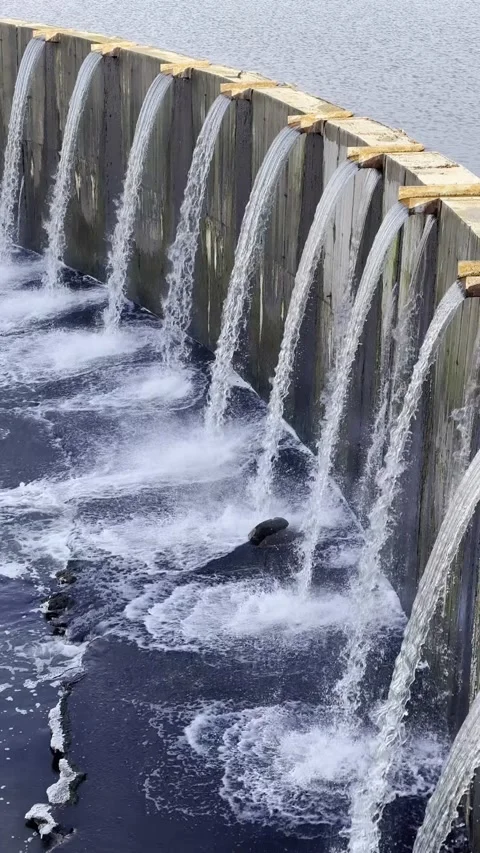 Close-up of a water flowing over concrete barrier. Row of thin trickles. Stock Footage 291228759