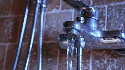 Close-up of water flowing from a silver-colored metal faucet in the bathroom of Stock Footage 221998050