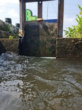 Close-up of Water Flowing Through a Rustic Sluice Gate in a Canal, Showing .. 库存照片