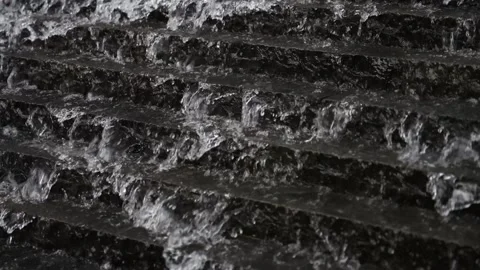 Close up of water flows down a large array of short black steps creating a big Stock Footage 300416954