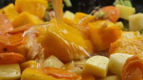Close-up of water poured on the pumpkin cubes with vegetables roasting on pan Stock Footage 234136845
