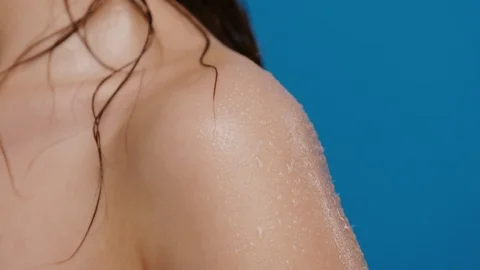 Close-up of water splashes falling down from wet woman shoulder isolated on blue Stock Footage 125044407