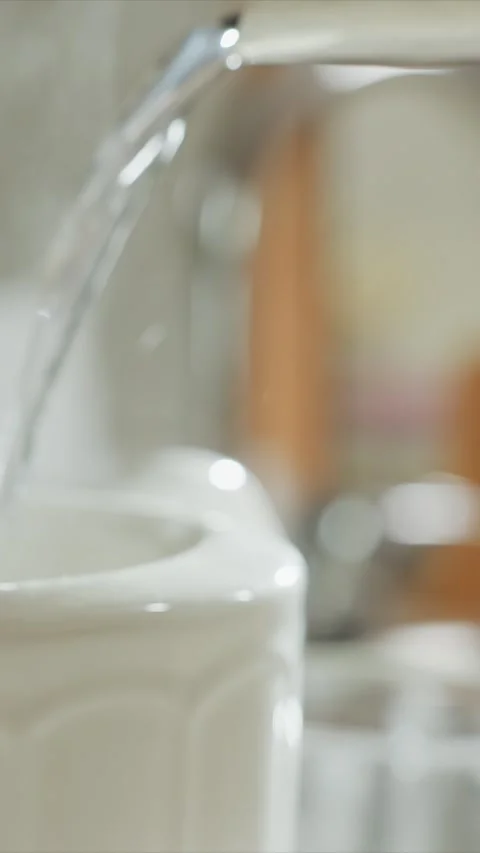 Close up of water steadily pouring into white ceramic containers from faucets Stock Footage 344420486