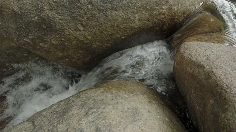 Close up water stream in jungle between boulders. Loop. Video stock 332397471