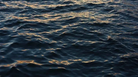 Close-up of water surface at sunset, waves reflect evening sunlight, abstract Stock-Footage 330286080