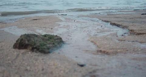 Close-up of water trickling down sand and rocks from a sea at a beach Video stock 127391045