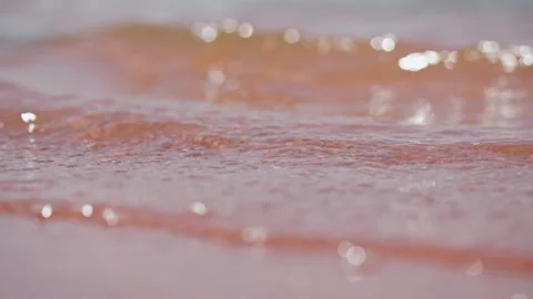 Close-up of water waves hitting the sand, waves washing over the beach. 動画素材 295419209