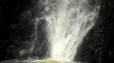 A close up of a waterfall flowing into a pool followed by a slow tilt upward. Stock Footage 9472079
