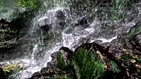 Close up of a waterfall, showing the clear water slowly hitting the dark rocks Stock Footage 336871273