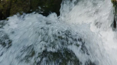 Close-up waterfall splash captures raw motion and forested backdrop Stock Footage 345710229