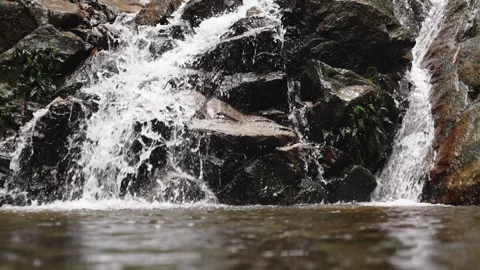 Close up of waterfall stream between dark rocks. Tropical freshness, powerful Stock Footage 309440192