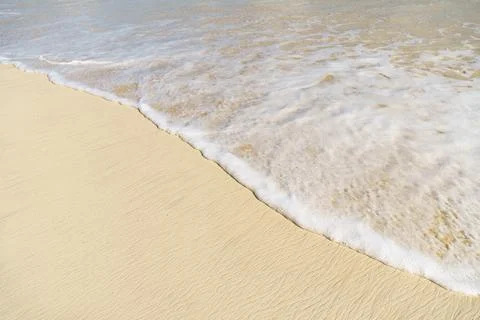 A close up of a wave breaking on a sandy beach with foamy waves Stock Photos