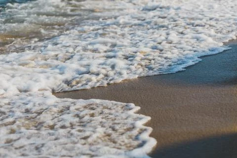 Close-up of a wave hitting a beach in warm sunset light Stock Photos