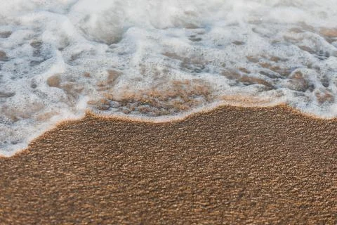 Close-up of a wave hitting a beach in warm sunset light Stock Photos