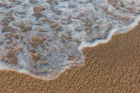 Close-up of a wave hitting a beach in warm sunset light Stock Photos