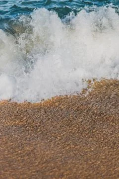 Close-up of a wave hitting a beach in warm sunset light Stock Photos