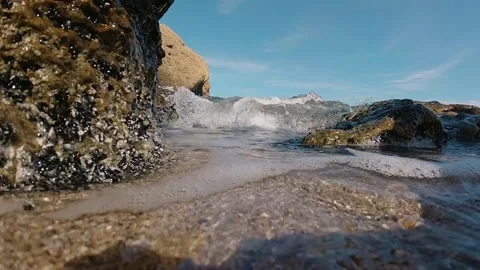 A close-up wave rolls over the camera on the shore of a sandy beach against the Stock Footage 150781376