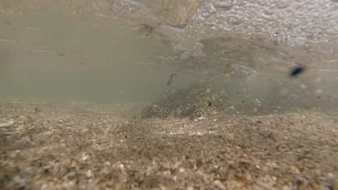 A close-up wave rolls over the camera on the shore of a sandy beach against the Stock Footage 151079960