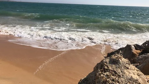 Close up of waves crashing on sandy beach rocks in summer Vilamoura Portugal Stock Footage 98414314