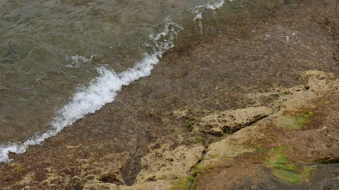 Close-up of waves gently rolling onto stone pier, breaking into soft splashes Video stock 332477722