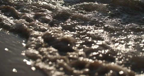 Close-up of waves reaching the shore in evening light Stock Footage 279902488