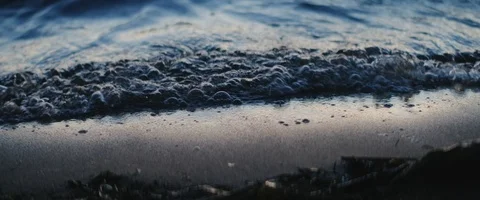 Close-up of waves rolling in during sunset. Filmed in anamorphic. Stock Footage