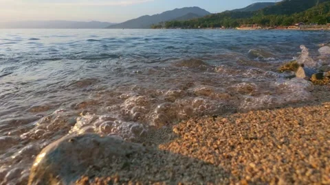 Close-Up of Waves on Sandy Beach at Sunset. Slow motion Stock Footage 303697938
