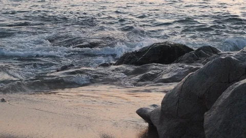 Close up of waves splashing against rocks on beach, slow zoom out Stock Footage 115999070