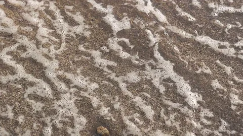Close up of waves washing over volcanic sand Stock Footage 84943710
