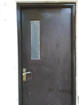 Close up of a weathered brown door featuring a mail slot and a brass latch, c Stock Photos