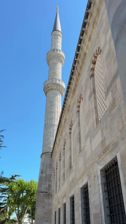 Close-up of a weathered marble wall with a blurred mosque minaret against a Stock Footage 340898172