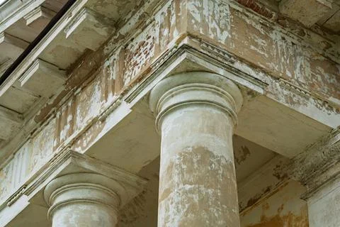 Close-up of weathered neoclassical column and peeling entablature highlight.. Фото