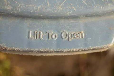 Close-up of a weathered plastic container lid with lift to open text 스톡 사진