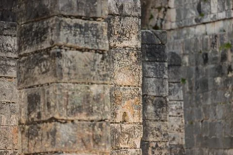 Close up of weathered stone columns with lichen patterns and carved glyphs at th Stock Photos