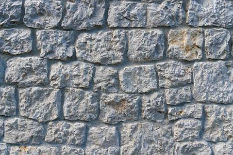 Close-up of a weathered stone wall with rough, textured blocks Stock Photos