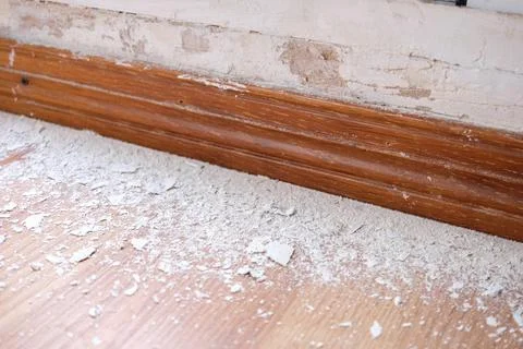 Close-up of a weathered wall with moisture damage and debris on the floor. Stock Photos