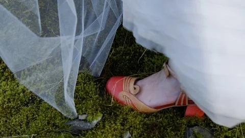 Close-up of wedding dress and shoes on mossy ground Stock Footage