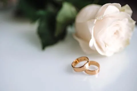 Close up of wedding ring on white table with white rose Stock Photos