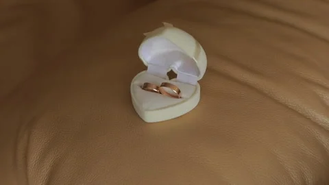 A close-up of wedding rings in a white box on the background of a white leather Stock Footage 321831693