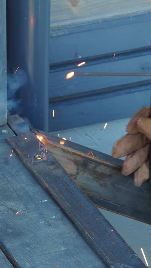 Close-up of a welder's hand using a welding torch, creating sparks as metal piec Stock Footage 312901405