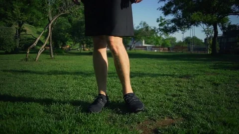 Close up well-built man ankle rotation exercises green meadow rapid slow motion Stock Footage 78037660