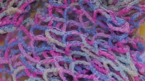 Close-up of a wet multi-colored knitted fishnet of blue, pink and white threads Stock Footage 343151926
