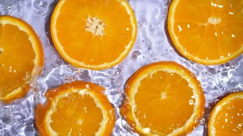 Close-up of wet orange fruit pattern in liquid with waves, commercial footage Stock Footage 341400560