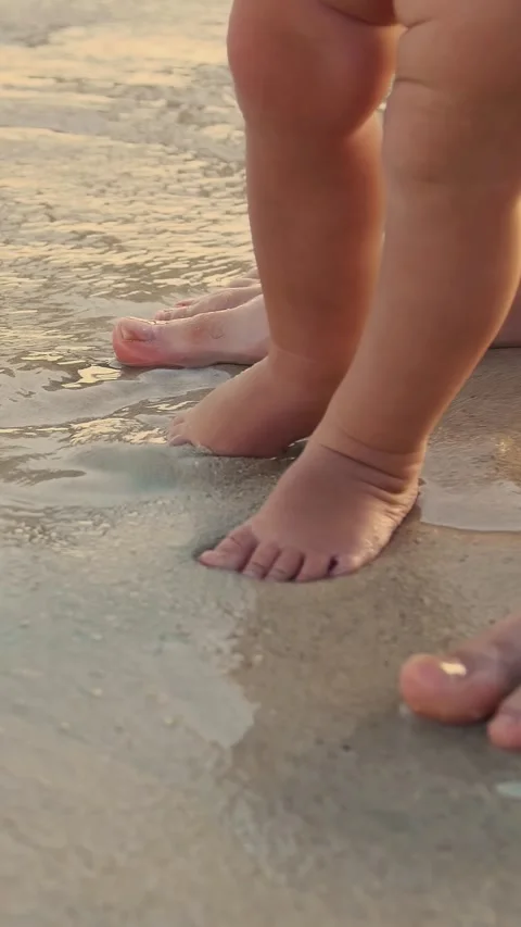 Close-up, on wet sand, there are male and children's feet. a wave comes in. Stock Footage 321615995