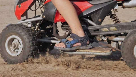 Close-up. The wheels of an ATV drive along a dirt road and throw sand out from Stock Footage 252729488