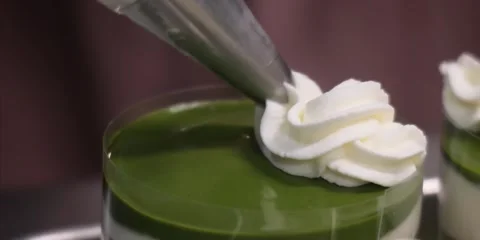 Close-Up of Whipped Cream Being Piped Onto a Matcha Green Tea Mousse Dessert Stock Footage 343589016
