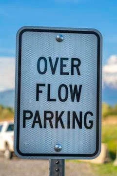 Close up of a white and black rectangular sign that reads Over Flow Parking 스톡 사진