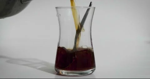 Close-up on white background. He pours Turkish tea into a special glass for Stock Footage 232316276